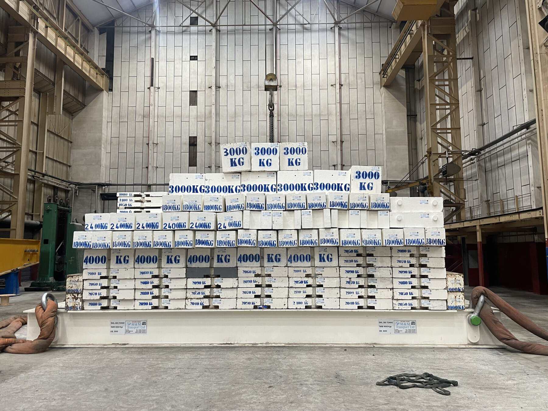 Stack of large 3000kg test weights in industrial setting.